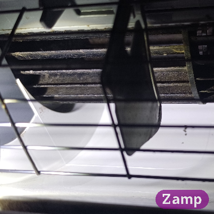 Aircon barrel fan behind a cage guard.